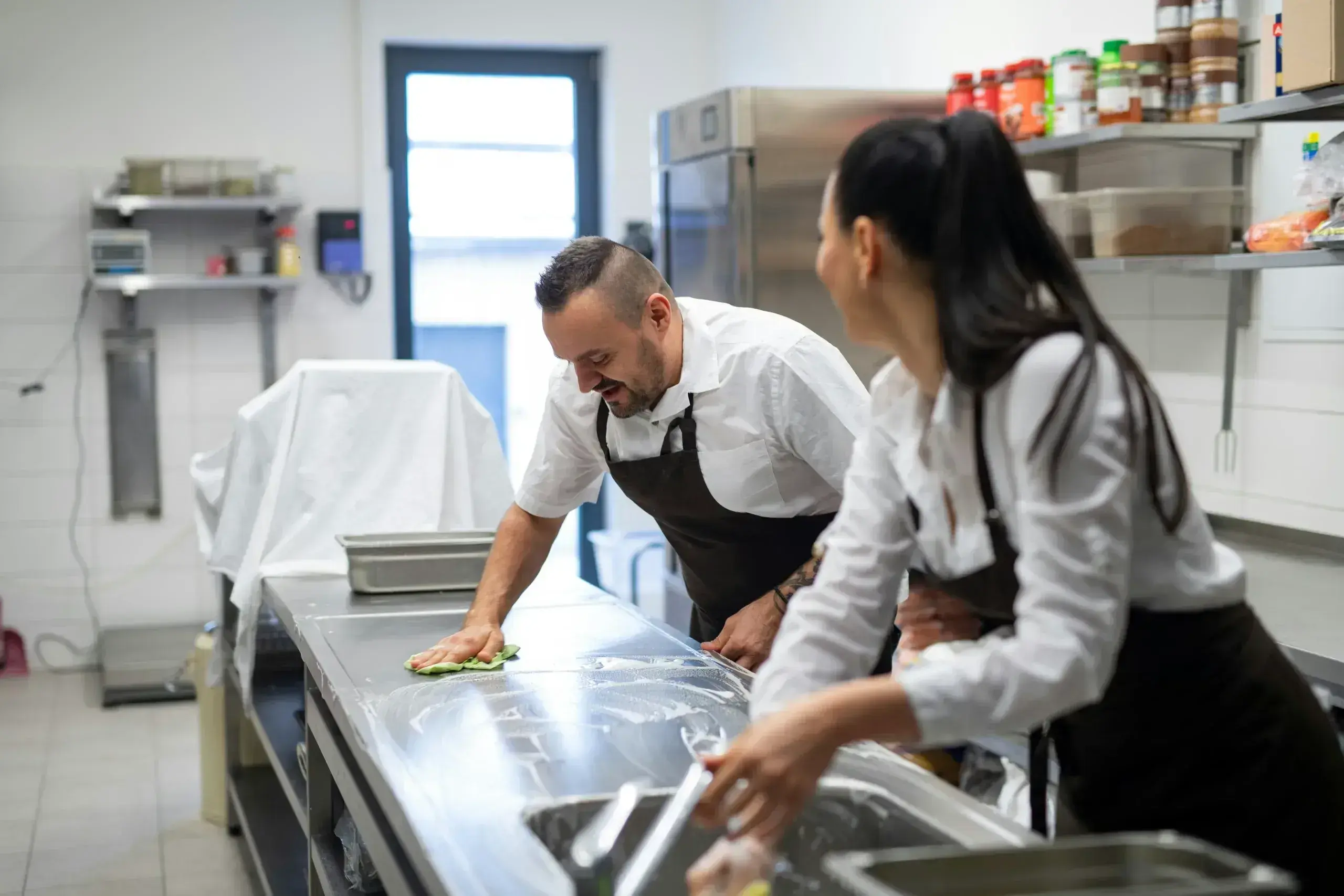 Chefs cleaning a kitchen countertop.